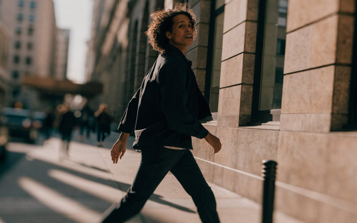 Person striding through a sunlit city street, full of energy